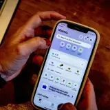 Dłoń trzyma smartfon z aplikacją Klarna. Czy Klarna jest bezpieczna? Aplikacja oferuje zakupy, płatności i zarządzanie zamówieniami.