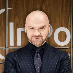 Łysy mężczyzna w garniturze przed panelem z napisem "InPost box". Tak, InPost jest polski!