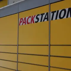 Żółta ściana z rzędami skrytek i napisem "PACKSTATION". To sieć punktów odbioru paczek, popularna także w Niemczech.