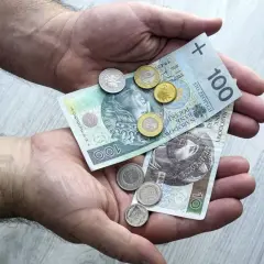 Dłonie trzymają polskie banknoty i monety. To pokazuje, co można sprzedawać w lombardzie, gdy potrzebne są szybkie pieniądze.