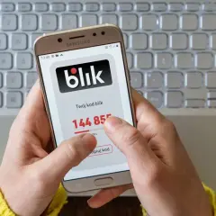 Dłoń trzyma smartfon z kodem blik. Szybki zwrot pieniędzy jest na wyciągnięcie ręki.