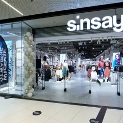 Sklep Sinsay w centrum handlowym, udekorowany balonami. W witrynie manekiny prezentują ubrania, a w środku widać regały z odzieżą.