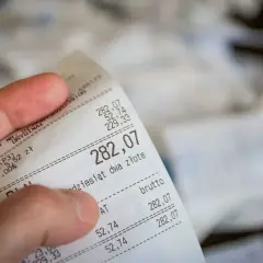 Dłoń trzyma rachunek za paliwo. Suma to 282,07 zł. Czy to będzie zwrot bez paragonu?