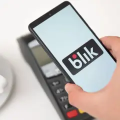 Płatność telefonem z logo Blik zbliża się do terminala. Czy Blik jest tylko w Polsce? Szybka transakcja przy kawie.