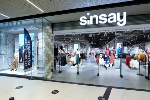 Sklep Sinsay w centrum handlowym, udekorowany balonami. W witrynie manekiny prezentują ubrania, a w środku widać regały z odzieżą.