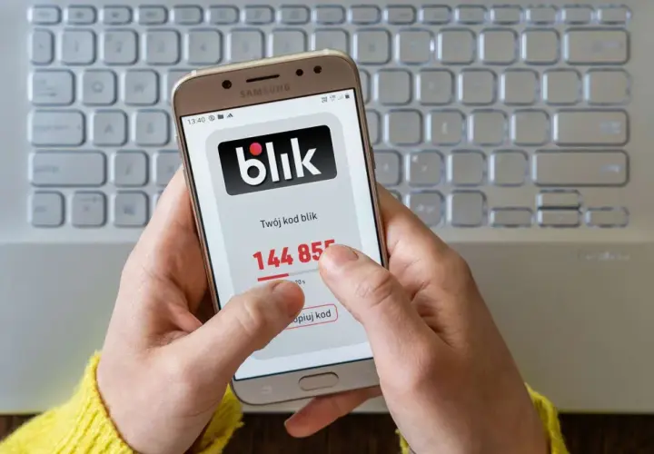 Dłoń trzyma smartfon z kodem blik. Szybki zwrot pieniędzy jest na wyciągnięcie ręki.