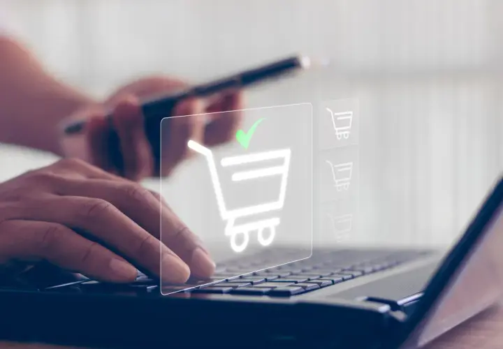 Dłonie wpisują dane na klawiaturze laptopa, a na ekranie pojawia się ikona koszyka z zielonym znacznikiem, symbolizująca udany zakup, jakby płatność przez paysafecard.