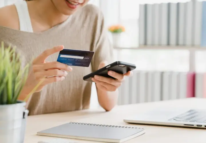 Kobieta płaci kartą przez telefon, korzystając z integracji **PayPal WooCommerce** do zakupów online.