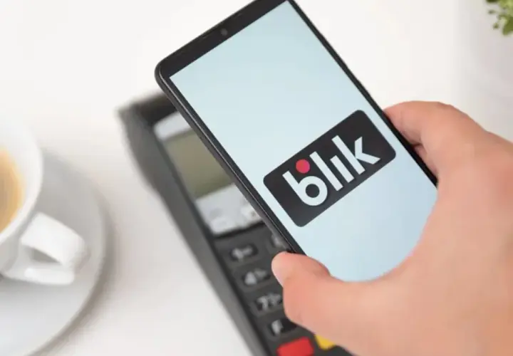 Płatność telefonem z logo Blik zbliża się do terminala. Czy Blik jest tylko w Polsce? Szybka transakcja przy kawie.