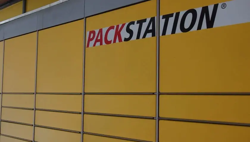 Żółta ściana z rzędami skrytek i napisem "PACKSTATION". To sieć punktów odbioru paczek, popularna także w Niemczech.
