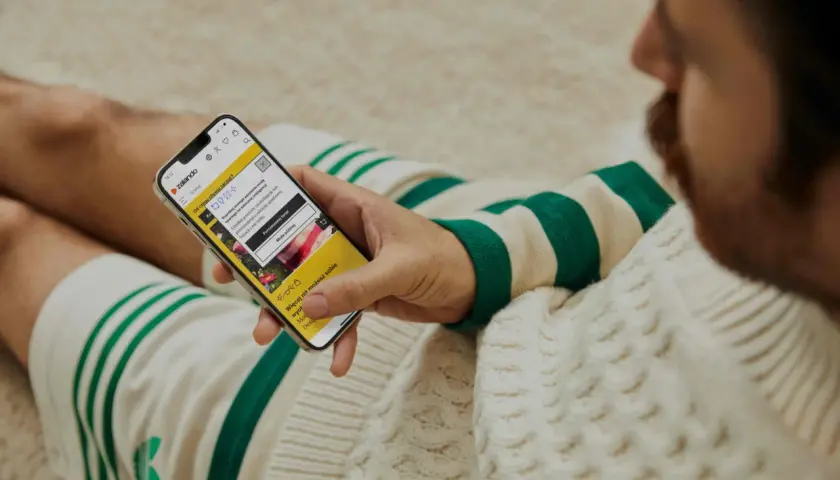 Mężczyzna przegląda telefon z aplikacją Zalando. Widoczna promocja: zalando - 15% na wszystko.