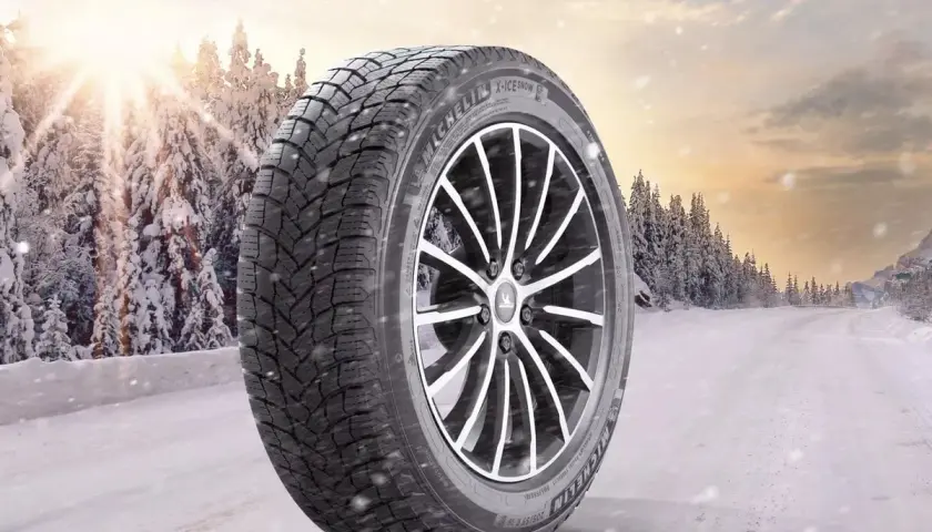 Opona zimowa Michelin X-Ice Snow 215/55R17 na tle zaśnieżonego lasu. Sprawdź nasz ranking opon zimowych!
