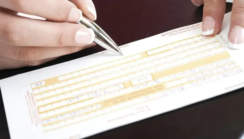Dłoń z długopisem wypełnia formularz przelewu tradycyjnego.