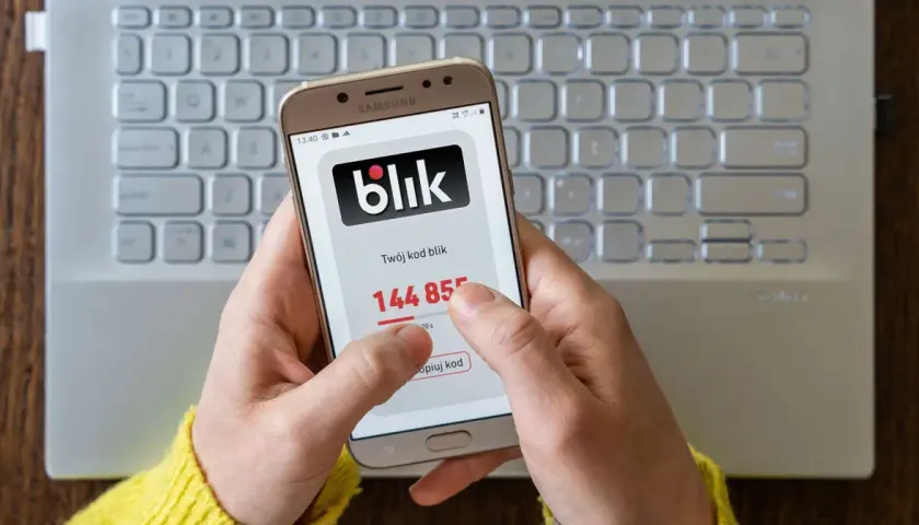 Dłoń trzyma smartfon z kodem blik. Szybki zwrot pieniędzy jest na wyciągnięcie ręki.