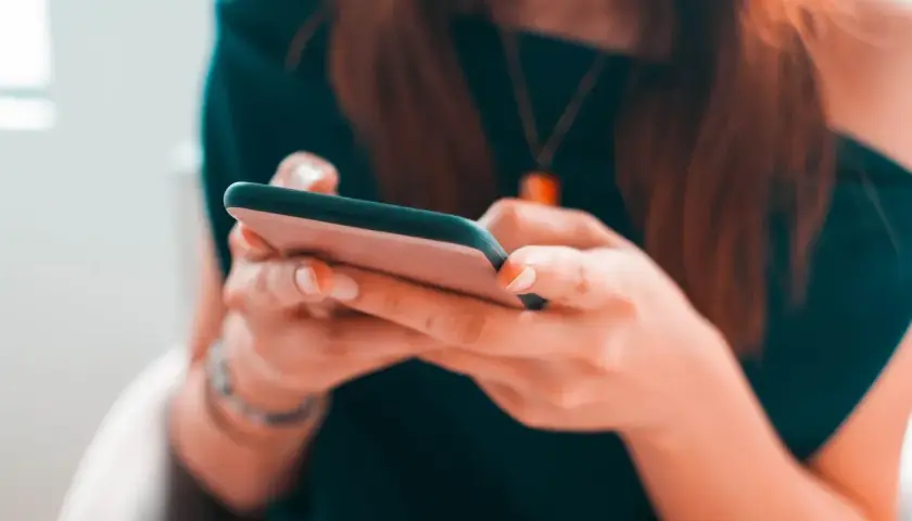 Kobieta pisze na telefonie, planując zakupy na Vinted z opcją PayPo.