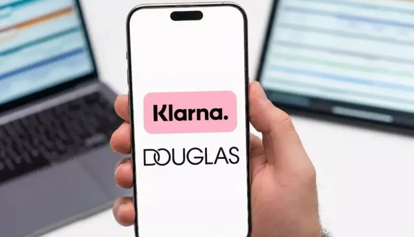 Dłoń trzyma smartfon z logo Klarna i Douglas. To ułatwia zakupy, jak douglas paypo.