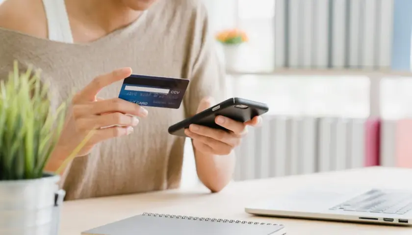 Kobieta płaci kartą przez telefon, korzystając z integracji **PayPal WooCommerce** do zakupów online.