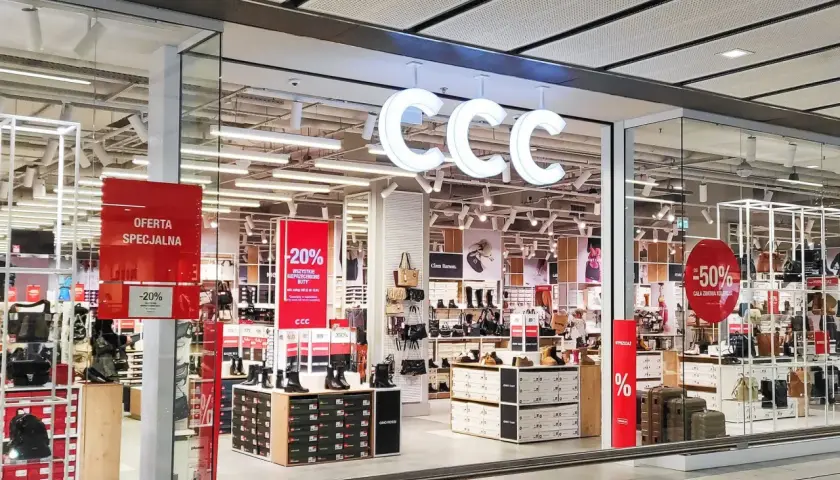 CCC - promocje w sklepach stacjonarnych. W witrynie sklepu CCC widoczne są wyprzedaże -20% i -50% na obuwie i torebki.