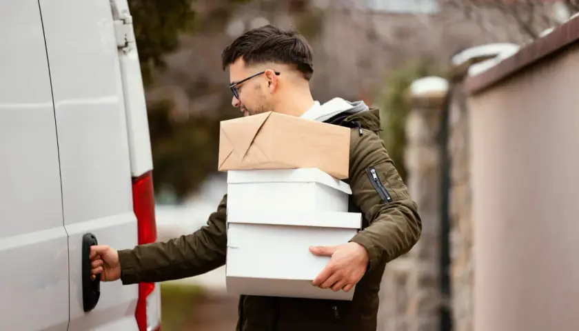 Kurier z kilkoma paczkami, gotowy do załadunku do białego vana. Kolejna paczka do Islandii w drodze!