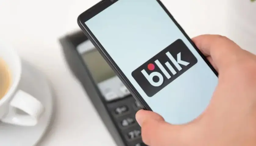 Płatność telefonem z logo Blik zbliża się do terminala. Czy Blik jest tylko w Polsce? Szybka transakcja przy kawie.