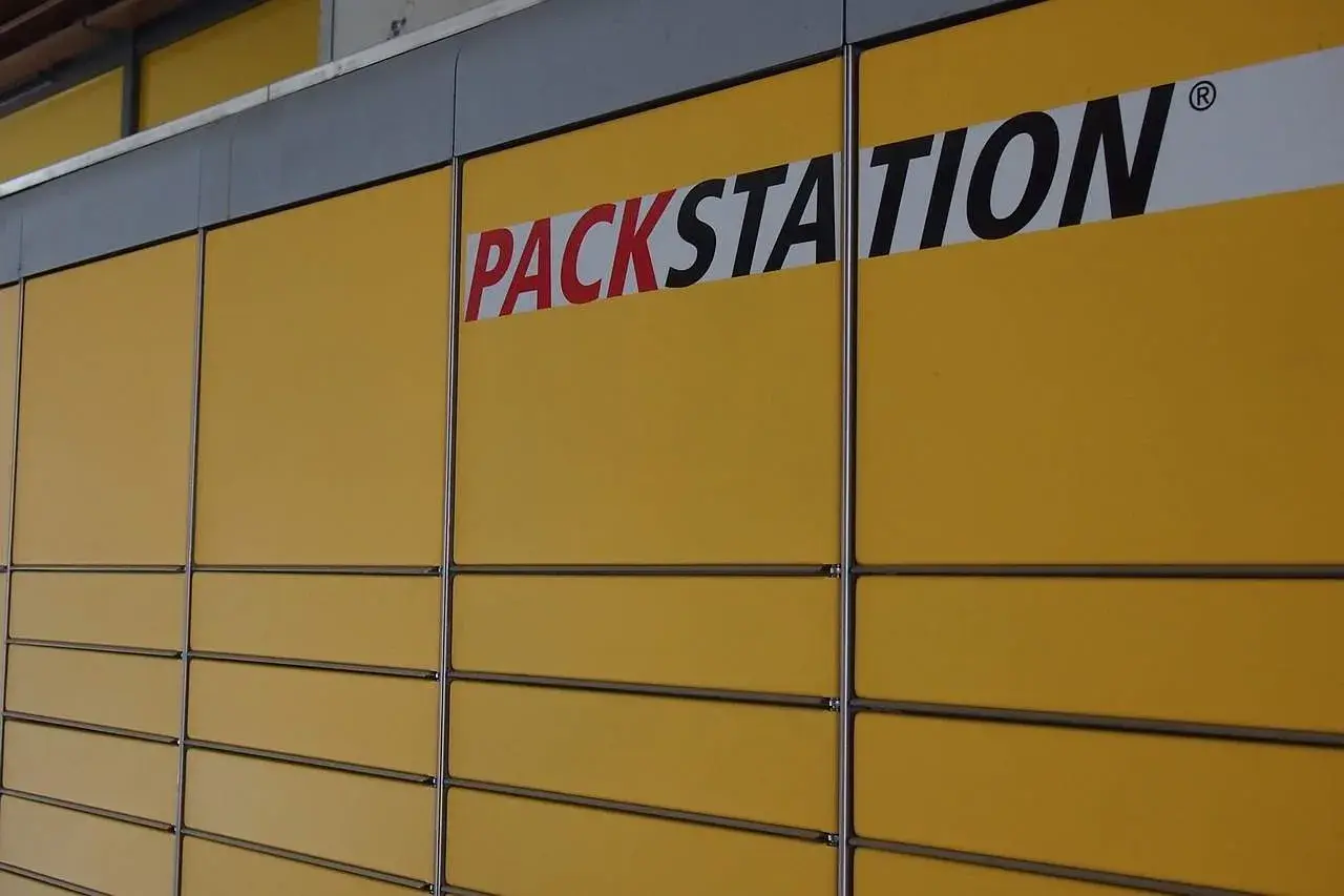 Żółta ściana z rzędami skrytek i napisem "PACKSTATION". To sieć punktów odbioru paczek, popularna także w Niemczech.
