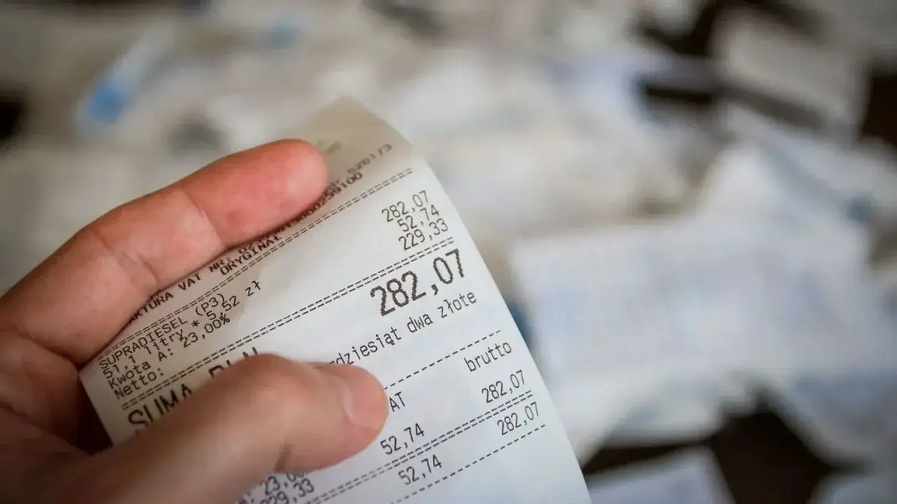 Dłoń trzyma rachunek za paliwo. Suma to 282,07 zł. Czy to będzie zwrot bez paragonu?