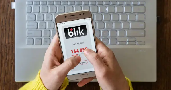 Dłoń trzyma smartfon z kodem blik. Szybki zwrot pieniędzy jest na wyciągnięcie ręki.